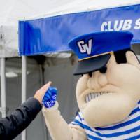 Louie fist bumps an alum at the Club Sports tent
